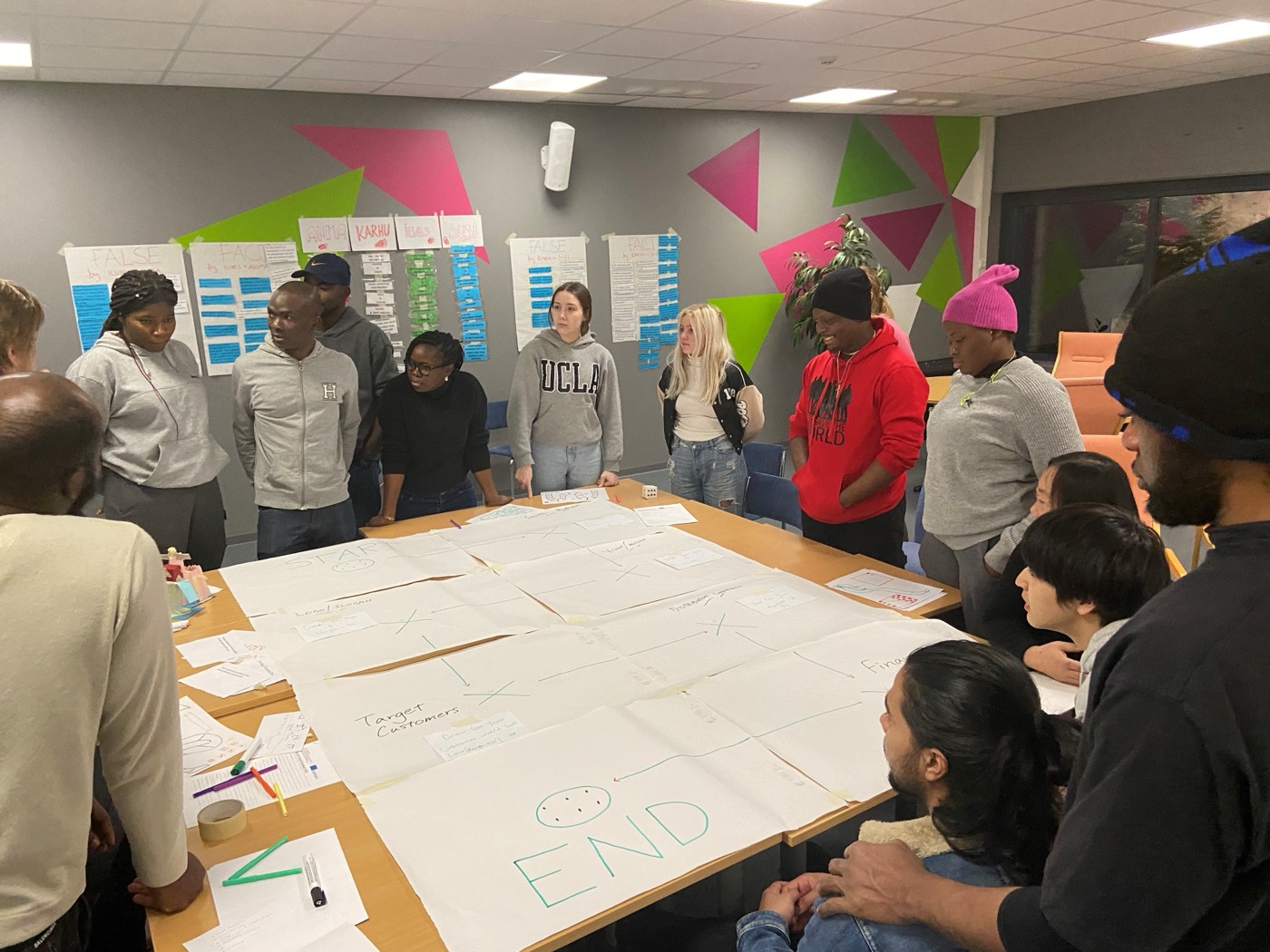 An international workshop group working around a table covered in plans